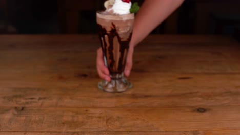 Detailed-close-up-of-chocolate-milkshake,-with-caramel-and-espresso-coffee,-removed-from-the-table-by-a-waiter