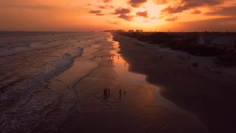 Tilting-drone-shot-showing-people-in-the-beach-in-sunset,-Brazil