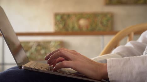 Closeup-shot-of-professional-female-employee-working-online-from-home,-typing-on-her-laptop-in-home-environment