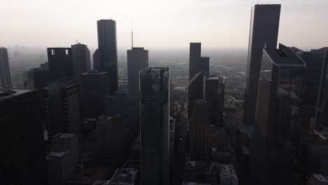 Flying-in-middle-of-buildings-in-downtown-Houston,-hazy-day-in-Texas,-USA---Aerial-view