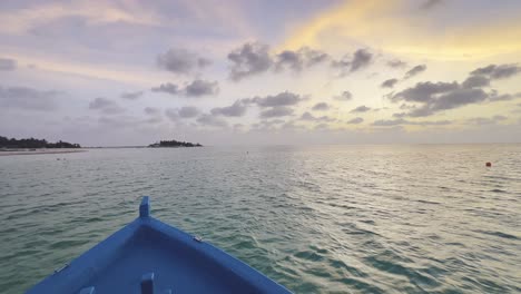 Scenic-Drive-on-a-Traditional-Dhoni-Boat-Across-the-Turquoise-Waters-of-Maldives,-as-the-Glorious-Sun-Descends-into-the-Horizon,-Painting-the-Sky-with-Hues-of-Gold-and-Orange