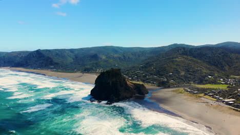 Lion-Rock-And-Piha-Black-Sand-Beach-Under-Bright-Blue-Sky-In-Auckland,-New-Zealand