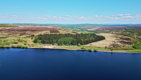 Serene-Winscar-Reservoir-in-Yorkshire-hosts-a-thrilling-boat-race-with-small-one-man-boats,-beneath-the-brilliant-midday-sun,-where-white-sails-compete-on-the-wonderful-blue-lake