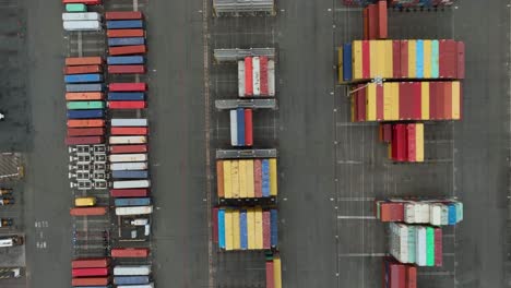 Top-down-aerial-view-of-shipping-containers-sitting-in-a-port,-waiting-to-be-shipped-around-the-globe