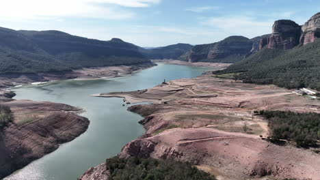Scenic-Sau-reservoir-aerial-view-flying-across-Ter-river-blue-sky-mountain-valley,-Catalonia,-Spain