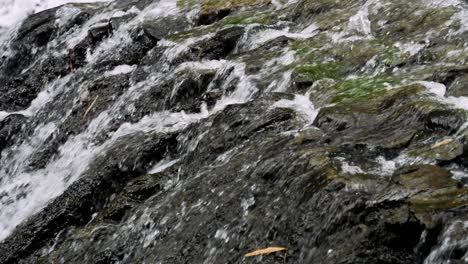 Close-up-slow-motion-shot-of-a-flowing-waterfall-with-view-of-the-stones-in-bali-indonesia