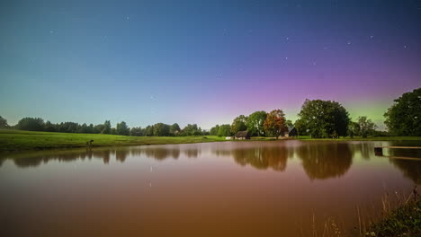 Aurora-borealis-appears-above-calm-later-water-surface,-time-lapse-view