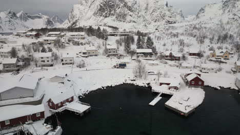 Luftaufnahme-Eines-Autos,-Das-Durch-Das-Verschneite-Dorf-Reine-Auf-Den-Lofoten,-Norwegen-Fährt