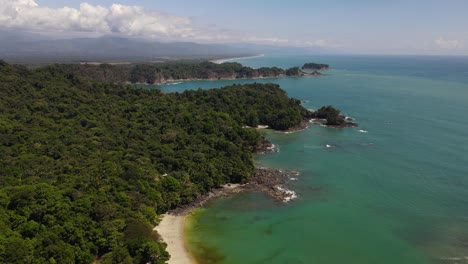 Aerial-pull-out-dolly-shot-of-Manuel-Antonio-tropical-beach-and-National-Park,-Costa-Rica