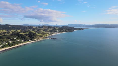 Beautiful-Aerial-View-Of-The-Lush-Green-Mountains-And-Blue-Ocean-Waters-Of-Matarangi-In-New-Zealand---aerial-shot