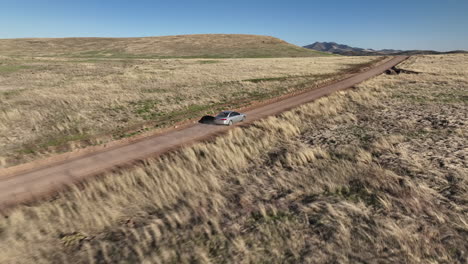 Drone-shot-of-car-driving-on-dirt-road-in-Willcox,-Arizona,-tracking-aerial-shot-drone-moves-behind-car