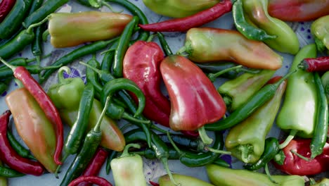 Colorful-thick-and-thin-pepper-fruits-on-table,-overhead-close-up-pan