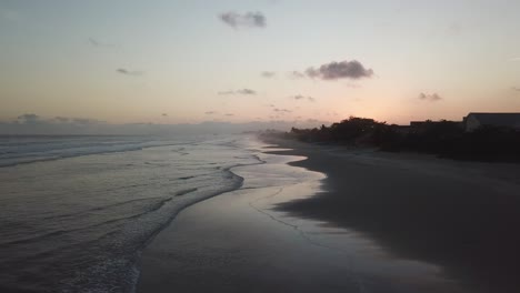 Descending-drone-shot-of-orange-skies-and-ocean-in-sunrise,-Itanhaem-Brazil