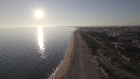 Aerial-pullback-along-Islantilla-beach,-Sunlight-reflection-on-Atlantic-Ocean,-Huelva,-Andalusia