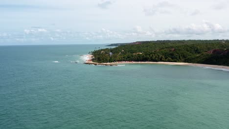 Dolly-En-Drone-Aéreo-Tiro-Extremo-De-La-Popular-Playa-Tropical-Coquerinhos-Cubierta-De-Sombrillas-Con-Turistas-Nadando-En-Una-Piscina-Natural-De-Un-Arrecife-En-Conde,-Paraiba,-Brasil