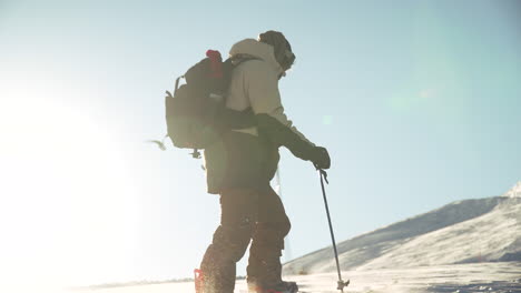 Male-backcountry-snowboarder-splitboard-skiing-atop-mountain-pass-blue-bird-sunny-fresh-snow-mountain-landscape-sunset-sun-flares-at-Vail-Pass-Colorado
