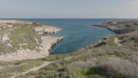 Aerial-Drone-shot-over-grass-towards-Kalanka-Bay-Malta