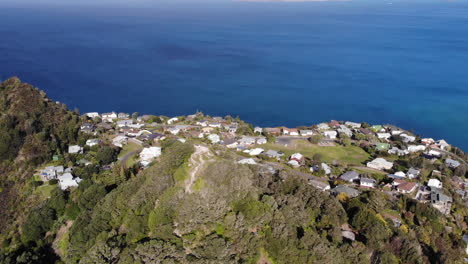 Aerial-View-of-Mount-Paku-Hill-Above-Pacific-Ocean-Coast-of-Coromandel-Peninsula-North-Island,-New-Zealand,-Tilt-Up-Pull-Back-Drone-Shot