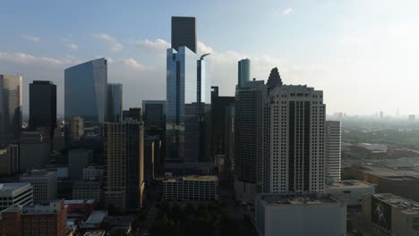 Aerial-view-around-the-downtown-Houston-skyline,-hazy,-sunny-day-in-Texas,-USA