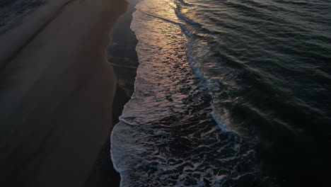 Revealing-drone-shot-starting-on-the-ocean-then-titling-up-to-reveal-the-sun-rising