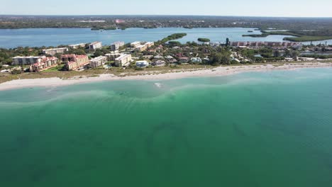 Drohnenclip-Bewegt-Sich-Vorwärts-über-Grünes-Meerwasser-In-Richtung-Strandgemeinde-Und-Häuser-In-Sarasota,-Florida
