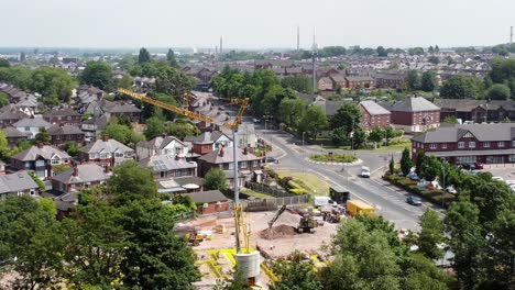 Tall-crane-setting-building-foundation-in-British-town-neighbourhood-aerial-view-above-suburban-townhouse-rooftops