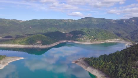 Breathtaking-4k-descending-aerial-shot-of-blue-sky,-lake,-mountains-and-forest