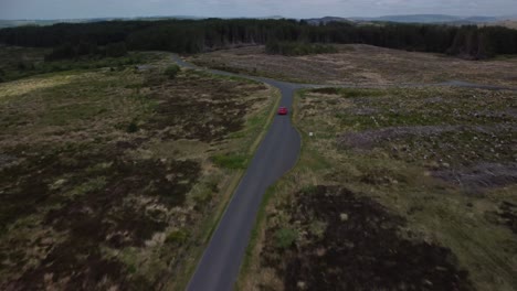Red-car-being-tracked-by-drone-travelling-on-a-single-track-country-road