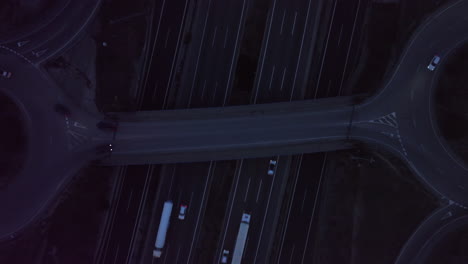 Aerial-view-rising-over-night-time-traffic-vehicles-travelling-busy-highway-interchange-overpass