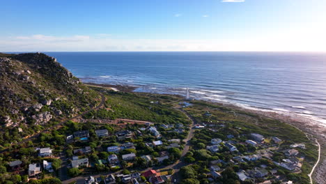 South-African-windy-Kommetjie-lighthouse-seaside-port-town-drone-aerial-cinematic-mid-day-afternoon-Cape-Town-Noordhoek-Chapman-Peak-stunning-spring-summer-deep-aqua-blue-ocean-circling-movement