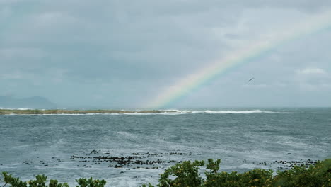 Möwen-Fliegen-über-Die-Küste-Mit-Regenbogen-über-Dem-Meer-In-Der-Ferne,-über-Dem-Strand