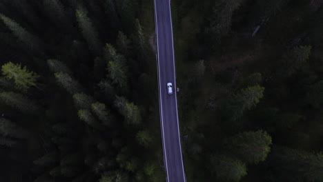 Drone-shot-tracking-a-car-on-a-asphalt,-forest-road,-in-cloudy-Dolomites,-Italy