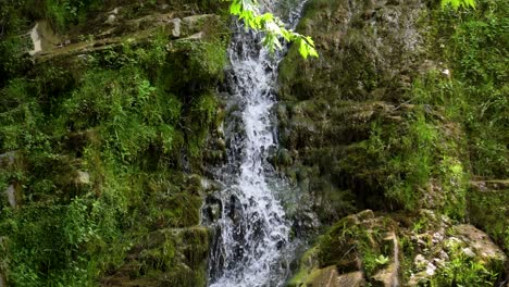 Slow-Motion-Of-Maries-Waterfall,-Surrounded-By-Lush-Green-Vegetation-And-Rocks-Covered-By-Moss,-Sun-Rays,-Thassos-Island,-Greece