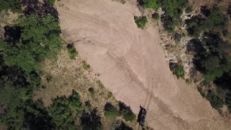 A-drone-shot-of-a-safari-vehicle-navigating-its-way-through-a-dried-up-river-bed-in-the-hot-afternoon-sun-in-Africa
