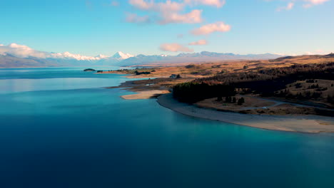 Flyover-turqoise-Lake-Pukaki,-reveal-of-majestic-scenery-of-Mt-Cook,-New-Zealand