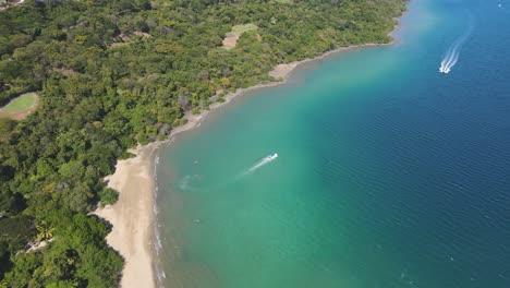 Aerial-Drone-Flyover-Turquoise-Blue-Nacascolo-Beach-With-Boat-In-Costa-Rica,-4K