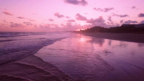 Stunning-establishing-aerial-shot-of-waves-and-beach-with-pink-sunset,-Brazil