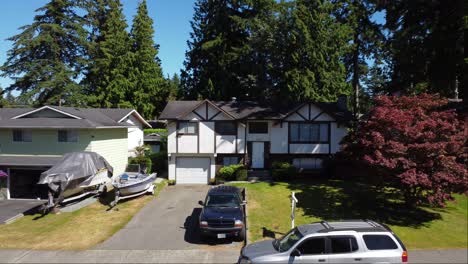 A-reverse-aerial-shot-reveals-a-large-single-family-home-in-the-residential-area-with-cars-parked-on-the-driveway-and-maple-trees-around-its-lawn