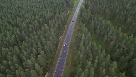 Vista-Aérea-De-Pájaro-Del-Camino-Forestal-En-Finlandia,-Dos-Autos-Pasando,-Drones-Siguiendo-Autos,-Tráfico-Rural,-Verano,-Día-Nublado