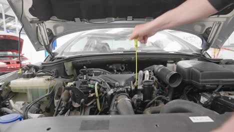 Person-removes-oil-stick-from-vehicle-engine-to-check-the-oil-level