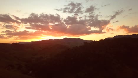 Atemberaubende-Luftaufnahme-Von-Hügeln-Im-Sonnenuntergang,-Farbenfroher-Sommerhimmel