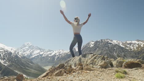 Woman-reaching-Sealy-Tarns-trail-viewpoint-looking-at-Mount-Cook-raising-arms
