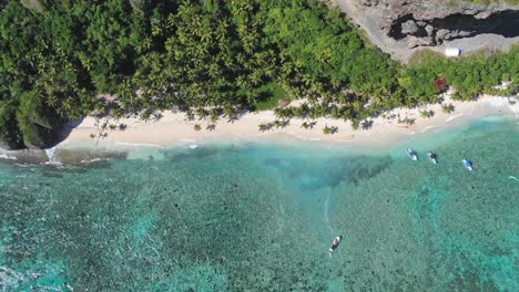 Picturesque-Sandy-Beach-Surrounded-By-Palm-Trees-And-Cliffs-In-Playa-Fronton,-Las-Galeras,-Samana,-Dominican-Republic---aerial-drone-shot