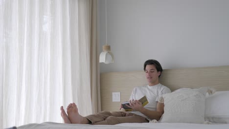 Caucasian-Man-Leaning-And-Sitting-On-Bed-While-Talking-To-Someone