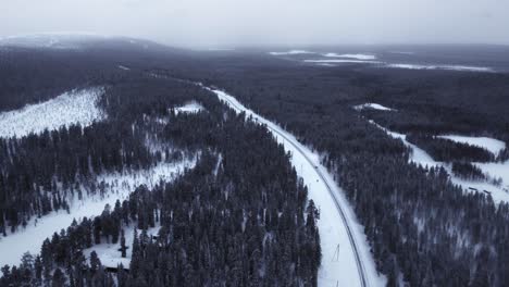 Vista-Aérea-Coches-Conduciendo-Carretera-Congelada-Cubierta-De-Nieve-Luosto-En-Laponia