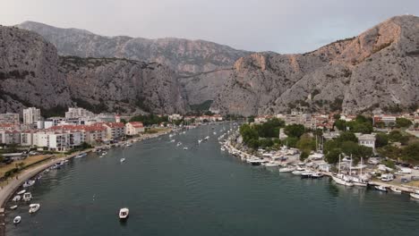 Aerial-view-of-Boats-and-Yachts-berthed-at-harbor-of-Cetina-river-mouth-pier-in-Omis-Town,-Croatia