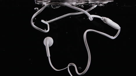 Alte-Kabelgebundene-Kopfhörer-Fallen-Ins-Wasser,-Wobei-Blasen-In-Zeitlupe-Zerstört-Werden