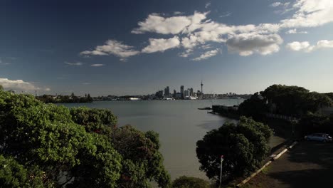 Amazing-drone-crane-reveal-Auckland,-New-Zealand-cityscape-over-lush-green-trees