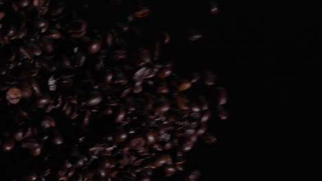 Vertikale-Zeitlupenaufnahme-Von-Kaffeebohnen,-Die-Vor-Schwarzem-Hintergrund-Fliegen