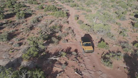 Luftaufnahme-Von-Oben:-Verfolgung-Eines-Geländewagens-In-Trockenem-Buschland-In-Moab,-Utah